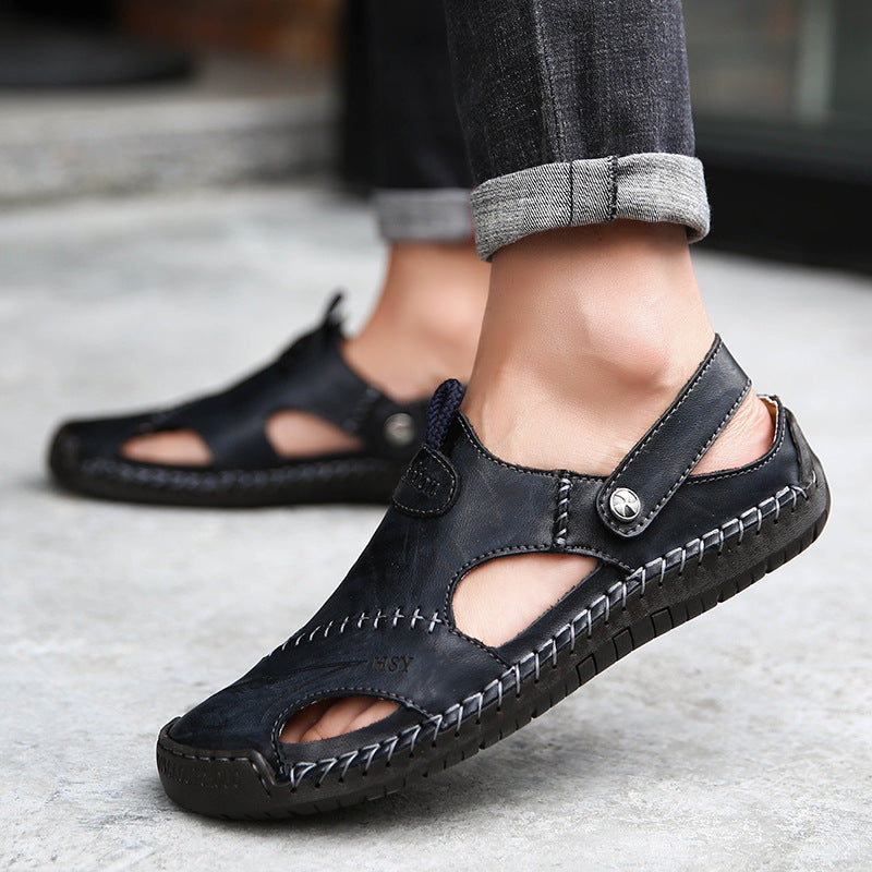 Black leather sandals worn by a person on a concrete surface