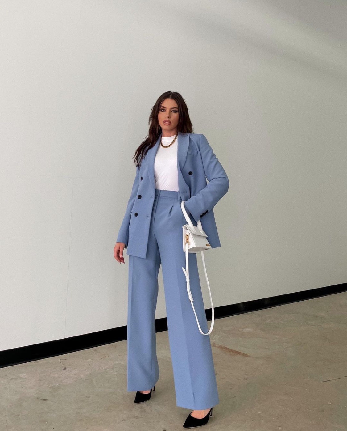 Woman in a blue suit standing against a plain wall. by millivan