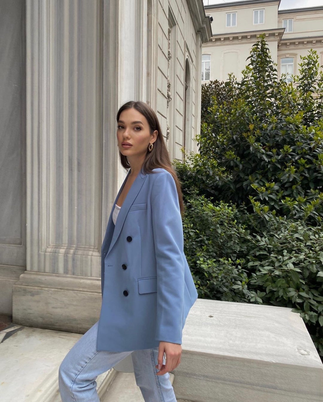 Woman in a light blue blazer standing in front of classical architecture by millivan