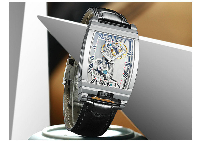 Luxury watch with black leather strap and silver case on a reflective surface