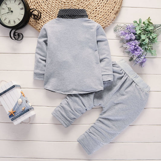 Children's gray outfit on a wooden surface with decorative items.