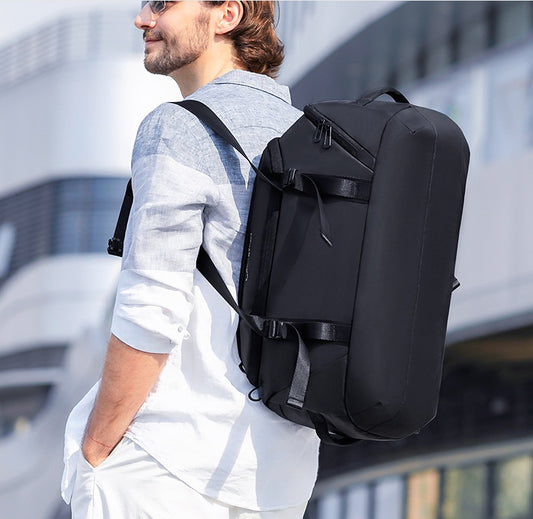 Man wearing a black backpack outdoors with a blurred background
