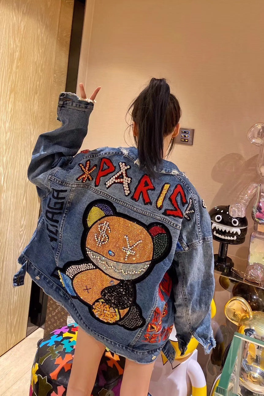 Person wearing a denim jacket with colorful patches and 'PARIS' text.