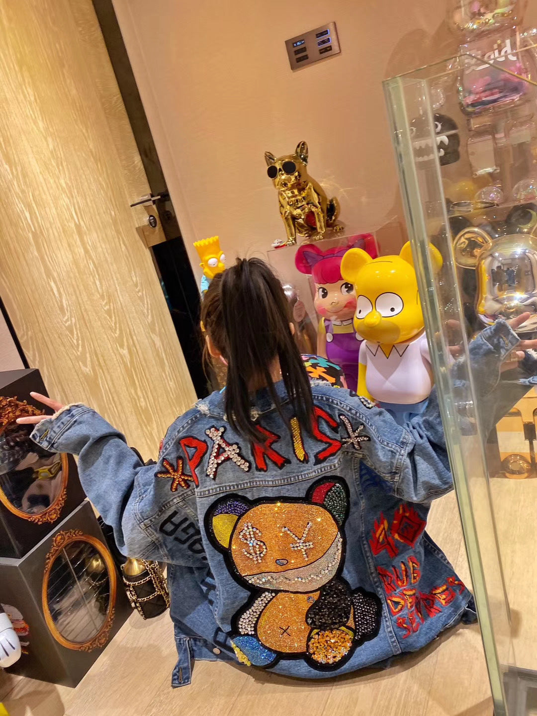Child wearing a denim jacket with colorful designs in a store setting