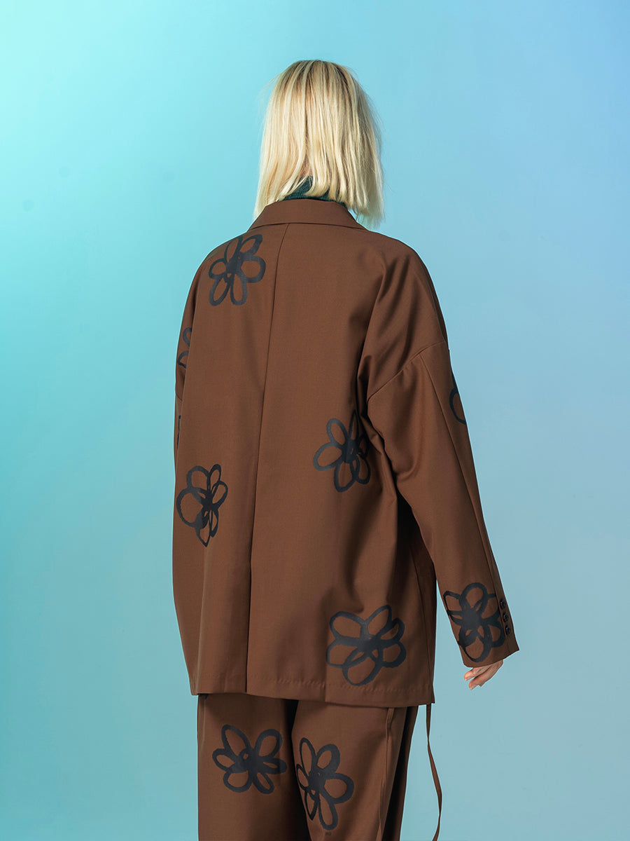 Person wearing a brown outfit with black floral patterns on a light blue background by Millivan 