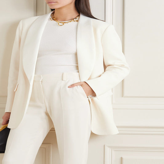 Person wearing a white suit with a gold necklace in an elegant interior setting by millivan