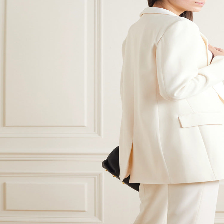 Person wearing a white suit against a light-colored wall. by millivan