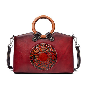 Red handbag with wooden handle and decorative emblem on a white background