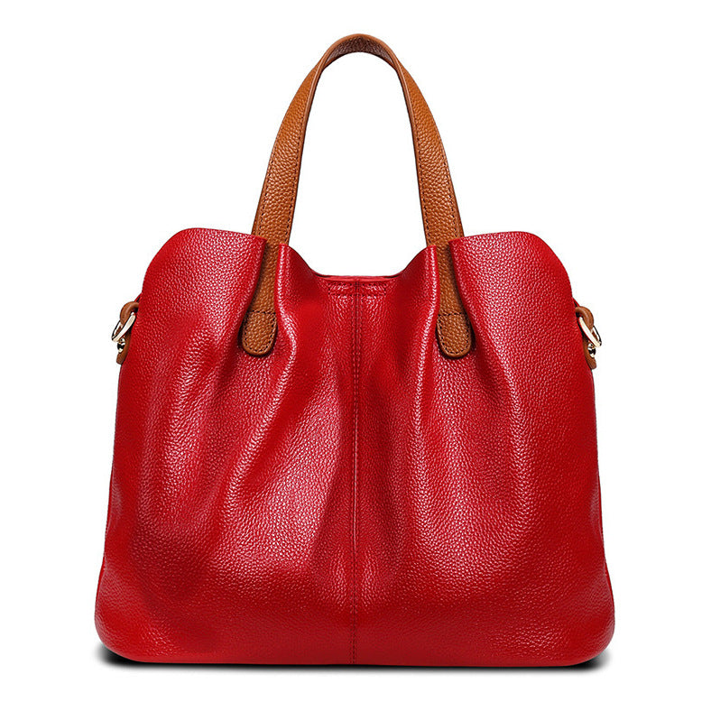 Red leather handbag with brown handles on a white background