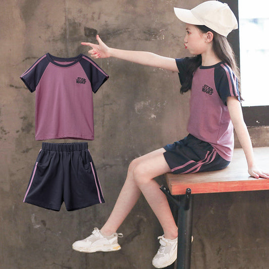 Child wearing a matching outfit with a shirt and shorts, sitting on a bench.