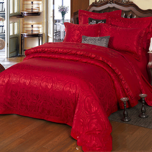 Red satin bedding set on a bed in a bedroom.