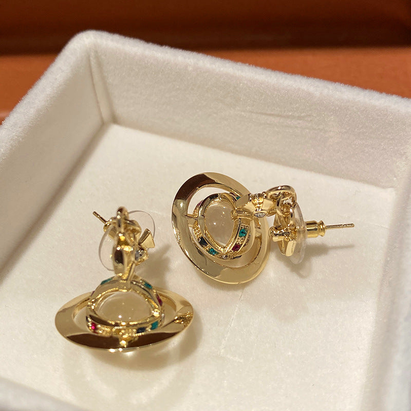 Gold earrings with gemstones in a white jewelry box
