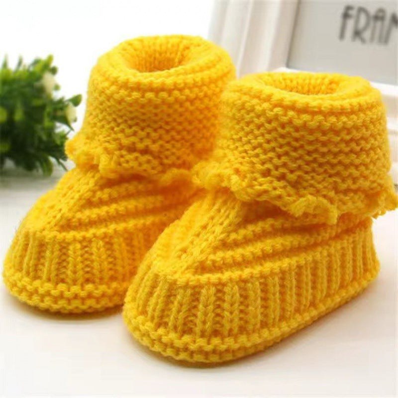 Pair of yellow knitted baby booties on a white background