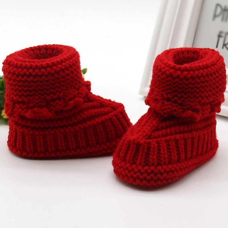 Red knitted baby booties on a white background