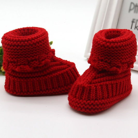 Red knitted baby booties on a white background