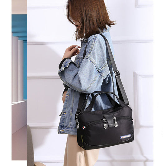 Person wearing a black backpack with a denim jacket against a white wall.