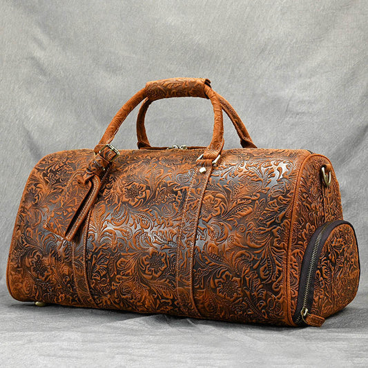 Brown leather duffel bag with intricate patterns on a gray background