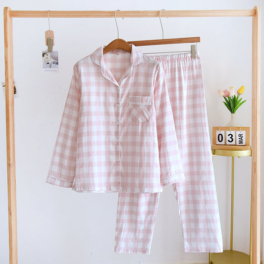 Pink and white checkered pajama set hanging on a wooden rack against a white wall.