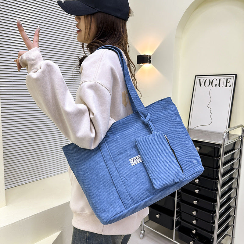 Person holding a blue tote bag in an indoor setting