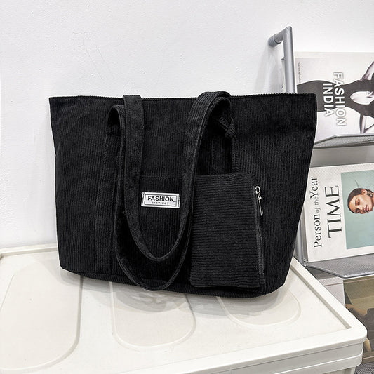 Black tote bag with a pocket on a surface with magazines in the background