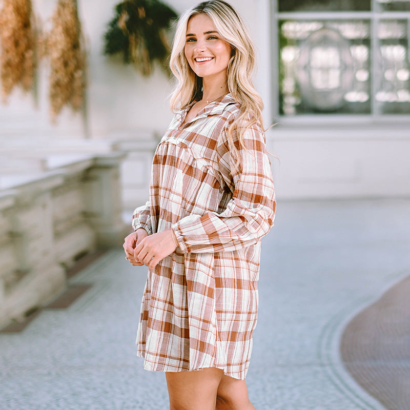 Woman wearing a plaid dress standing in an outdoor setting.
