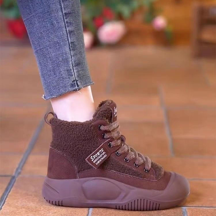 Brown high-top sneaker worn on a tiled floor with blurred background