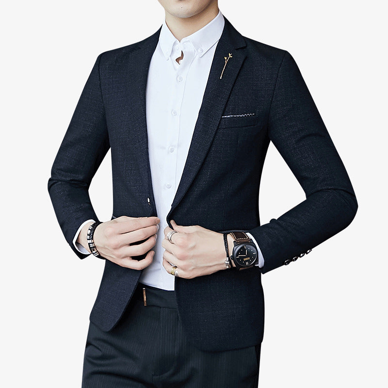 Man wearing a dark suit jacket over a white shirt on a light gray background
