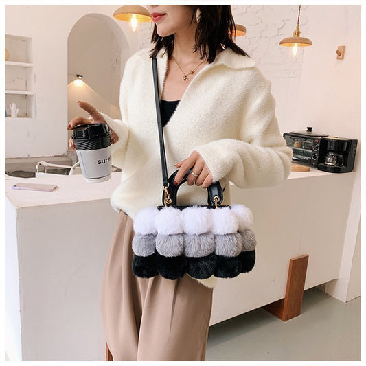 Person holding a handbag with pom-pom details in a kitchen setting