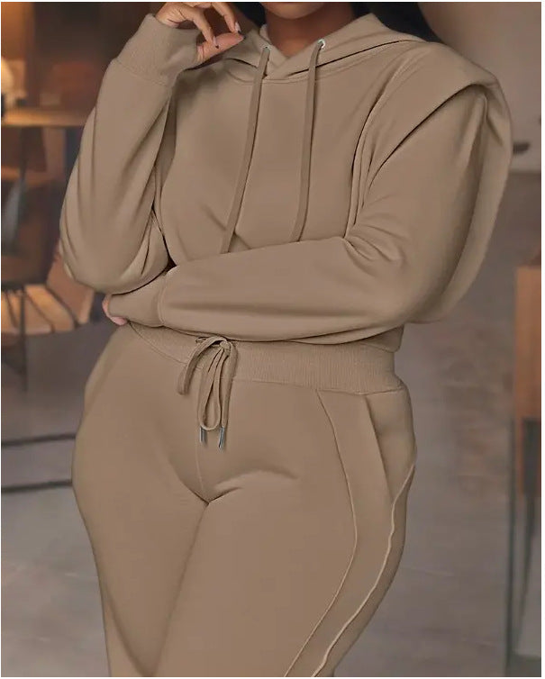 Person wearing a beige hoodie and jogger set in an indoor setting