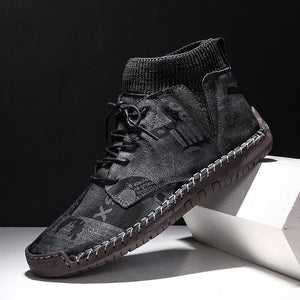 Black high-top sneaker with brown sole on a white surface with black background