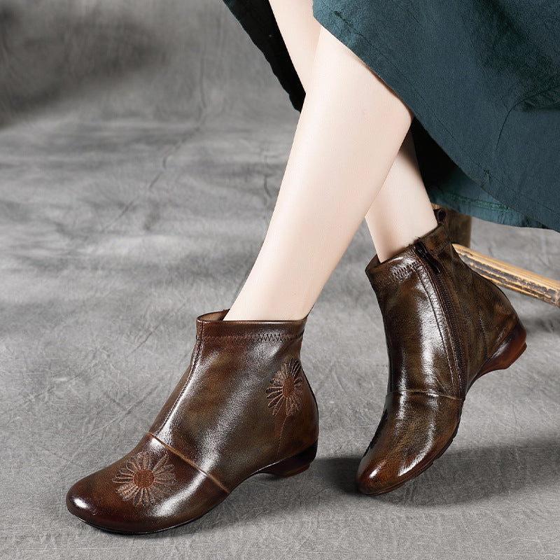 Brown leather ankle boots with floral embroidery on a gray background