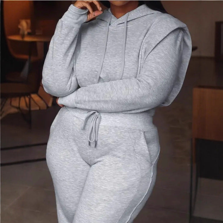 Person wearing a gray hoodie and jogger set in an indoor setting