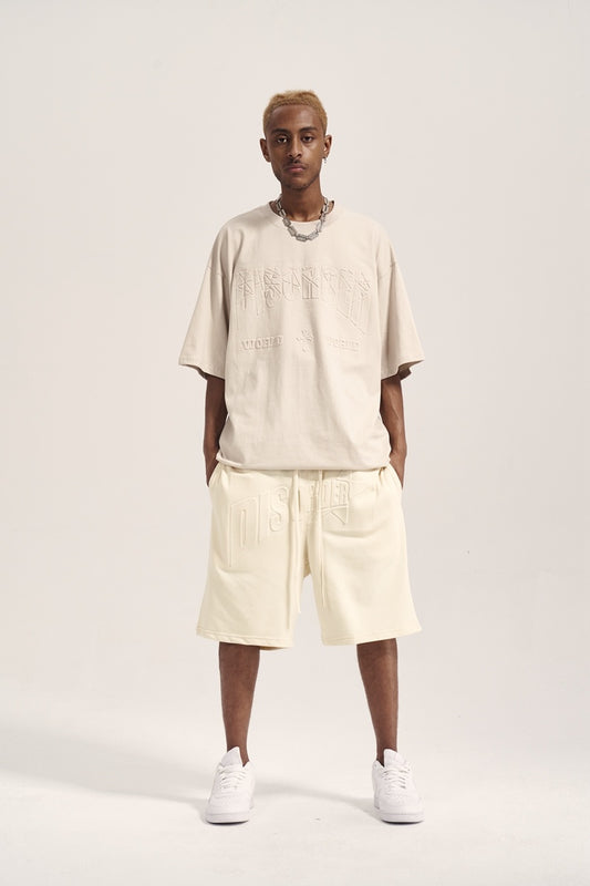 Person wearing a beige t-shirt and shorts set with white sneakers on a light gray background
