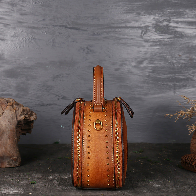 Brown leather handbag with gold accents on a dark background