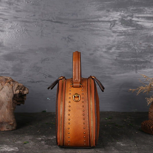 Brown leather handbag with gold accents on a dark background