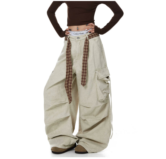 Beige cargo pants with plaid belt and brown long-sleeve top on a white background