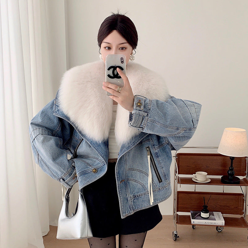 Person wearing a denim jacket with white fur lining, taking a mirror selfie.
