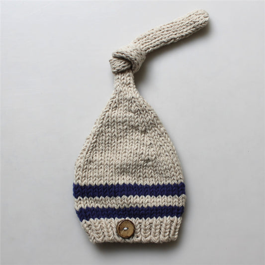 Knitted baby hat with a button on a light gray background