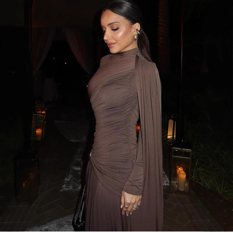 Woman in a brown dress standing in a dimly lit outdoor setting with candles.