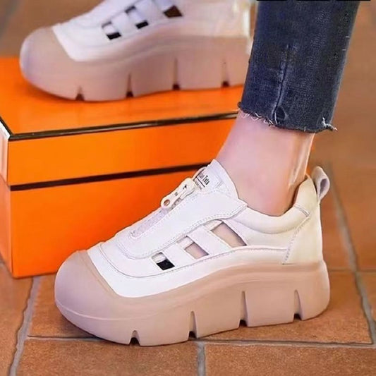 White and beige sneakers worn with orange box in the background