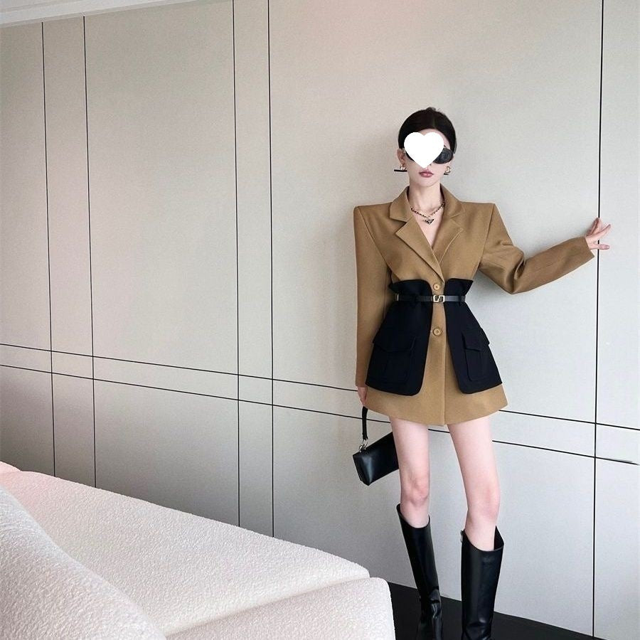 Woman in a stylish outfit with a beige coat and black skirt against a neutral wall.