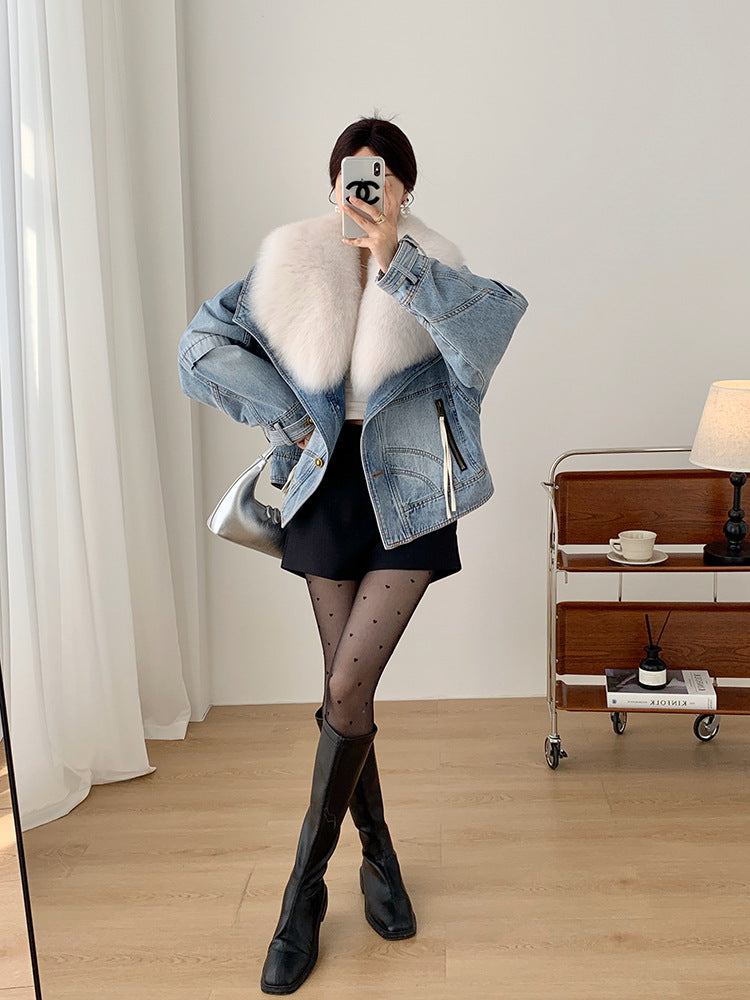 Person wearing a denim jacket with white fur lining, black skirt, and knee-high boots in a room.