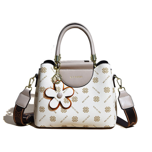 White handbag with gold floral design and matching strap on a white background