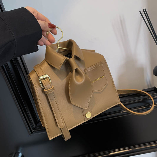 Brown leather handbag with gold accents on a hanger against a neutral background