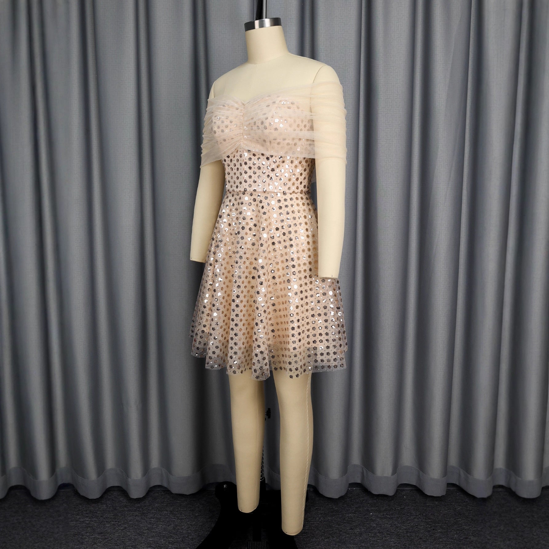 Mannequin wearing a polka dot dress against a gray curtain background