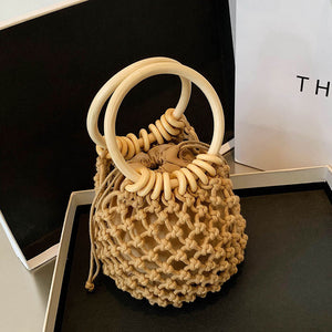 Beige woven handbag with wooden handles on a dark surface