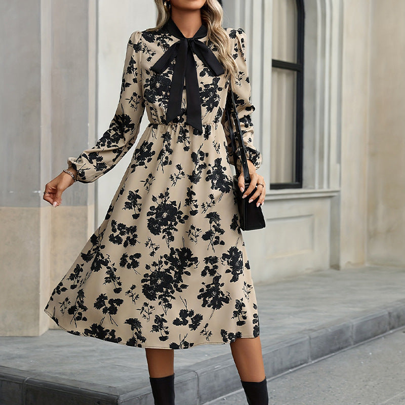 Woman wearing a floral dress with a black bow tie in an urban setting.