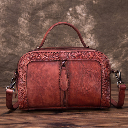 Brown leather handbag with intricate designs on a wooden surface and brown background