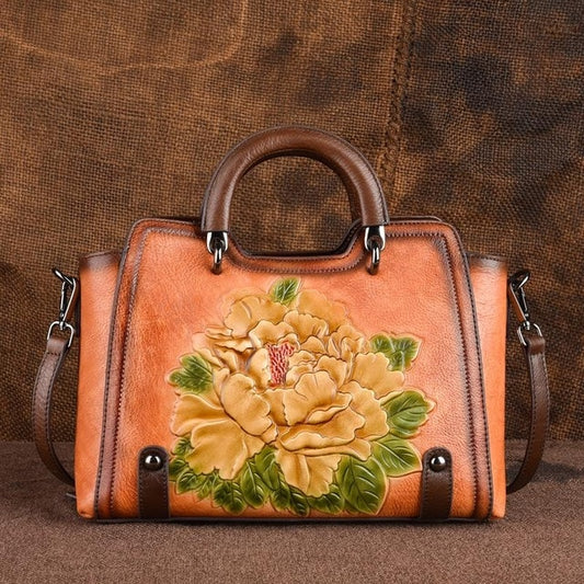 Brown leather handbag with floral design on a brown background