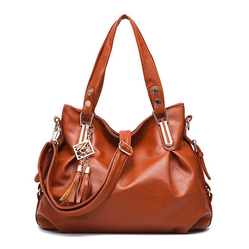 Brown leather handbag with gold accents on a white background